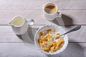 Corn Flakes cereal in a bowl, glass with milk and cap with espresso coffee. Morning breakfast.