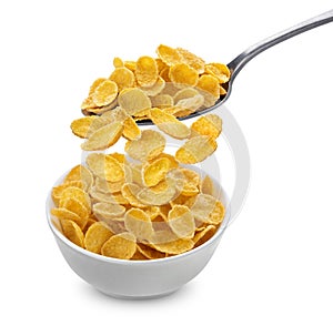 Corn flakes falling from spoon into bowl isolated on white background