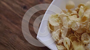 Corn flakes falling in white bowl with copyspace to the right. Close up view