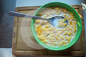 Corn flakes with milk in a bowl with a spoon