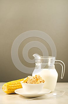 corn with flakes and milk/ corn flakes with milk and a corn ear on a gray background with copy space