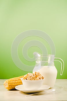 corn with flakes and milk/ corn flakes with milk and a corn ear on a green background with copy space