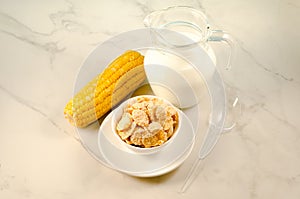 corn with flakes and milk/corn flakes with milk and a corn ear on a marble table