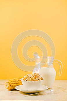 corn with flakes and milk/ corn flakes with milk and a corn ear on a yellow background