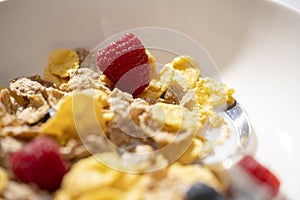 corn flakes with milk and raspberries in white bowl. Selective focus