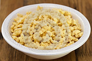 Corn flakes in white bowl on brown background