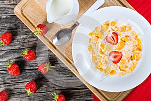 Corn flakes wirh milk and strawberries, top view