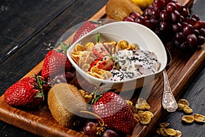 Corn flakes with yogurt and chia seeds. Assorted juicy ripe fruits. Strawberry, kiwi, apple, pear, banana, grapes