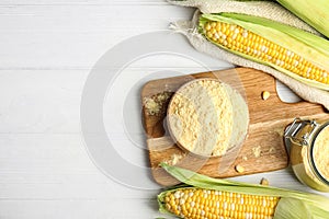 Corn flour in bowl on white wooden table, flat lay. Space for text