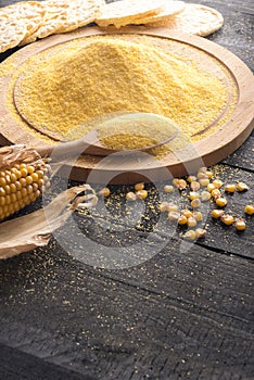 Corn flour on wooden board and grains