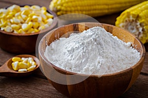 Corn flour in wooden bowl and corn cobs on table