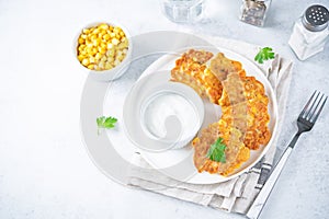 Corn fritters in a plate with sour cream sauce