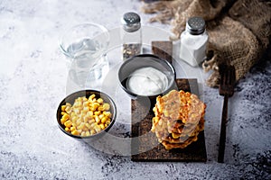 Corn fritters in a plate with sour cream sauce