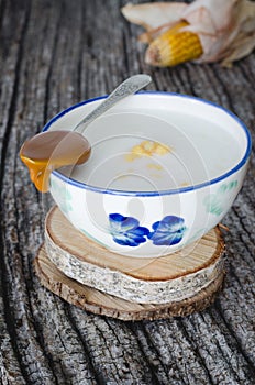 Corn grains cooked with spoon and dulce de leche on wooden background. Typical Colombian dish mazamorra.