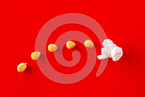 Corn grains transforming into a popcorn on red background