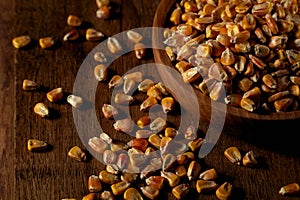 Corn grains in a wooden bowl and in bulk on a wooden table