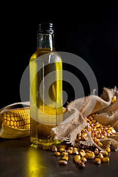 Corn oil with cobs on black background
