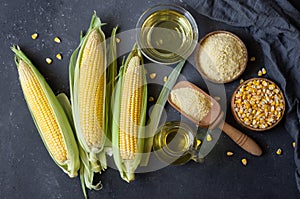 Corn oil and corn flour with fresh corncobs on rustic table