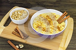 Corn porridge with cinnamon and peanuts on a wooden stand