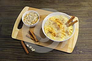 Corn porridge with cinnamon and peanuts on a wooden stand