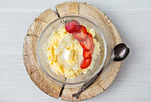 Corn porridge with strawberries - breakfast served on natural sawed wood with vintage spoon