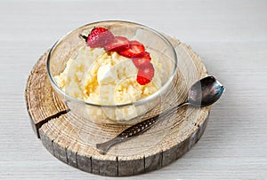 Corn porridge with strawberries - breakfast served on natural sawed wood with vintage spoon