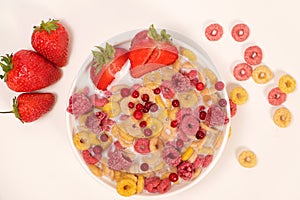 Corn rings with milk in a plate with berries and fruits, viewed from above on a white background. The concept of quick