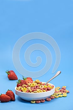 Corn rings with milk in a plate with berries and fruits on a white background. The concept of quick breakfast cereals