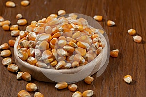 Corn seeds in wooden dish on wooden table