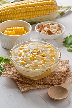 Corn soup in glass bowl and crispy bread with corn on white table