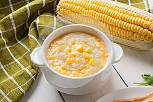 Corn soup in white bowl and corn on white table