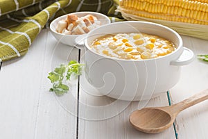 Corn soup in white bowl and crispy bread with corn on white table