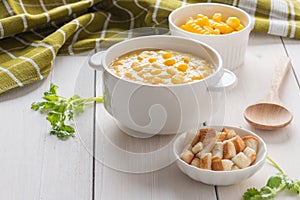 Corn soup in white bowl and crispy bread with corn on white table
