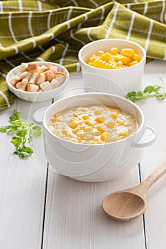 Corn soup in white bowl and crispy bread with corn on white table