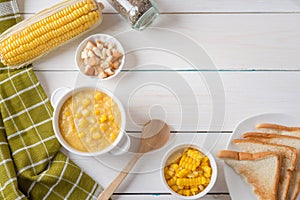 Corn soup in white bowl and crispy bread with corn on white table. Top view with Copy space