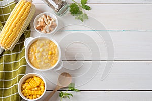 Corn soup in white bowl and crispy bread with corn on white table. Top view with Copy space