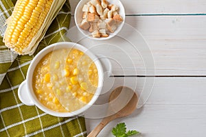 Corn soup in white bowl and crispy bread with corn on white table. Top view with Copy space