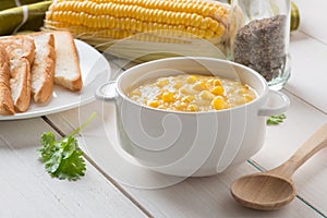 Corn soup in white bowl and toast with corn on white table