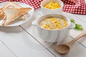 Corn soup in white bowl and toast with corn on white table