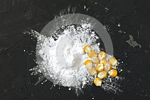 Corn starch with yellow grains on a black background, top view. Corn white starch and yellow kernels on the table