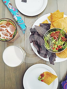 Corn tortilla chips and guacamole on table with cocktails