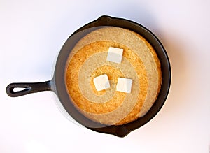 Cornbread with slices of melted butter in a cast iron skillet is