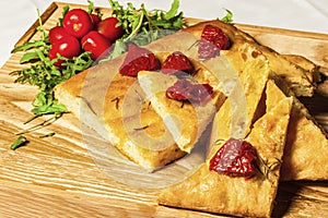 Cornbread on a wooden board with dried tomato and cherry tomatoes