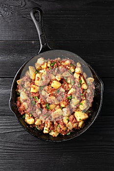 Corned beef hash with potatoes in iron cast pan