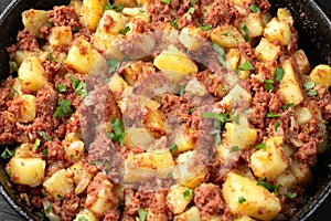 Corned beef hash with potatoes in iron cast pan