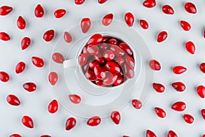 Cornel berries in a cup with saucer top view on a white background