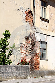 Corner of abandoned suburban family house heavily damaged by missile and shrapnel during war on dilapidated facade