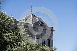 Corner of an ancient monumental building surrounded by leafy trees