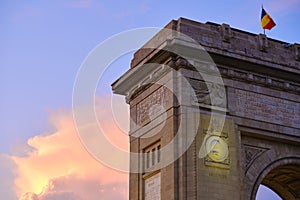 A corner of the Arch of Triumph in Bucharest, Romania, during a sunset with pink and orange clouds. Main touristic landmark.