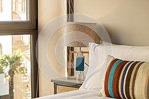 corner of a bedroom with colorful striped headboard, pillows, cushions